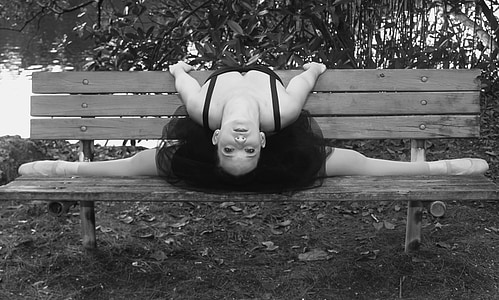 grayscale photography of ballerina on brown wooden bench