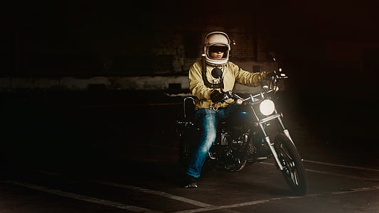 man in yellow jacket and blue jeans riding on black motorcycle