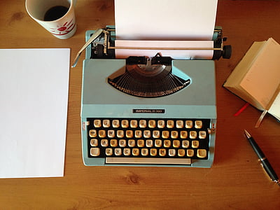 blue and beige typewriter on top of brown wooden table