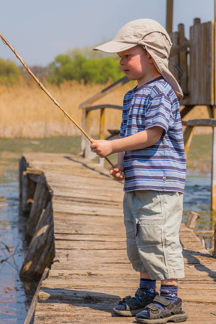 boy in blue and black stripe shirt holding fishing rod