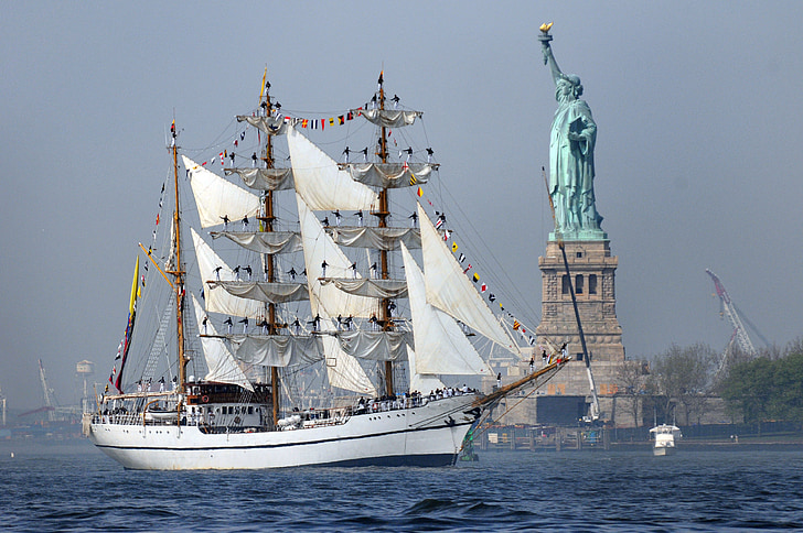 photo of white sailing ship near Statue of Liberty