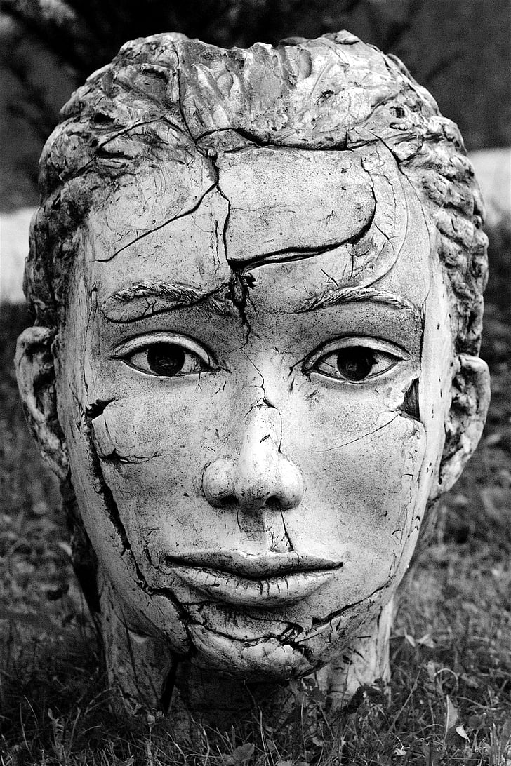 grayscale photography of cracked head bust on ground