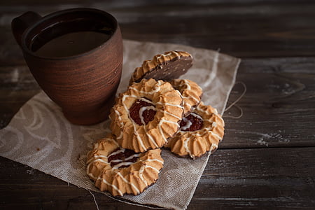 brown ceramic mug beside baked cookies on brown wooden surface