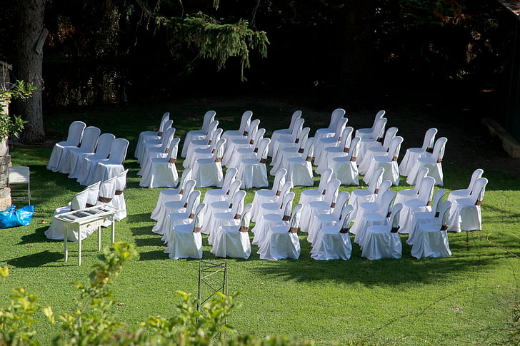 white covered chairs filed horizontally on green lawn