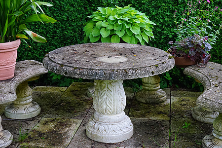 round grey concrete pedestal table with benches and plants