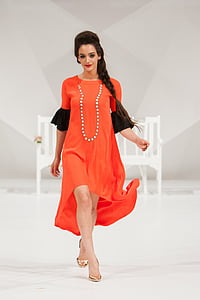 woman wearing orange and black elbow-sleeved maxi dress walking on flooor