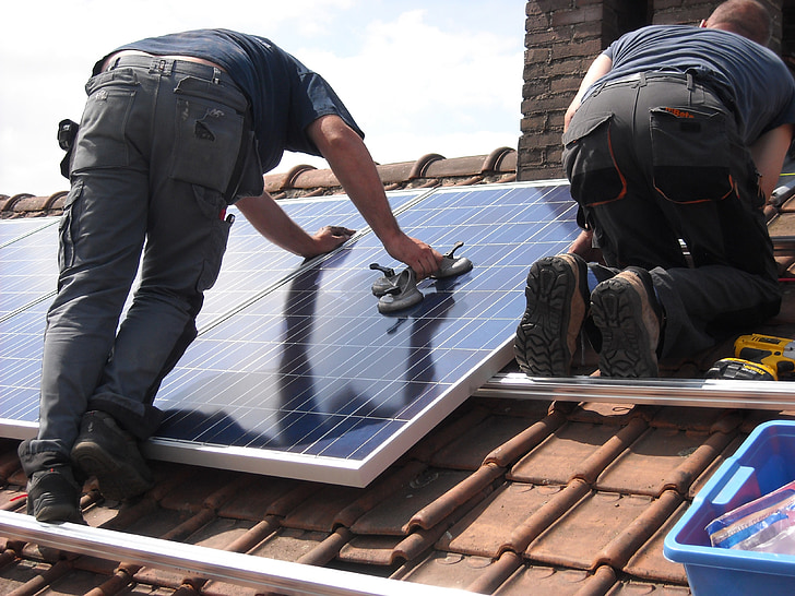 man putting solar panel board on roof during daytime