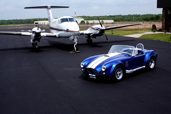 blue and white convertible near white airliner on road