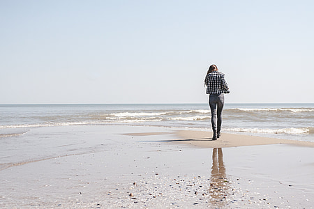 woman in white and black blazer walking on seashore