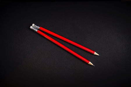 two red pencils on black background