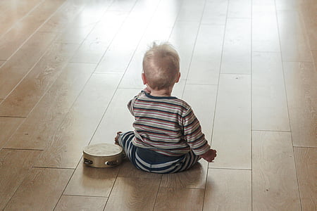 boy's white and black striped long-sleeved shirt sits near tambourine