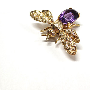 purple gemstone and gold-colored bee brooch