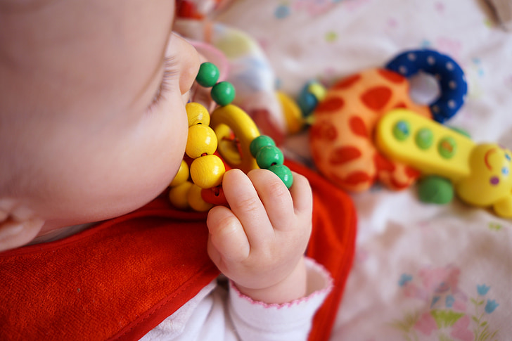 baby biting yellow and green toy