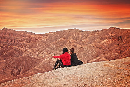 two women sitting on hill looking at hills