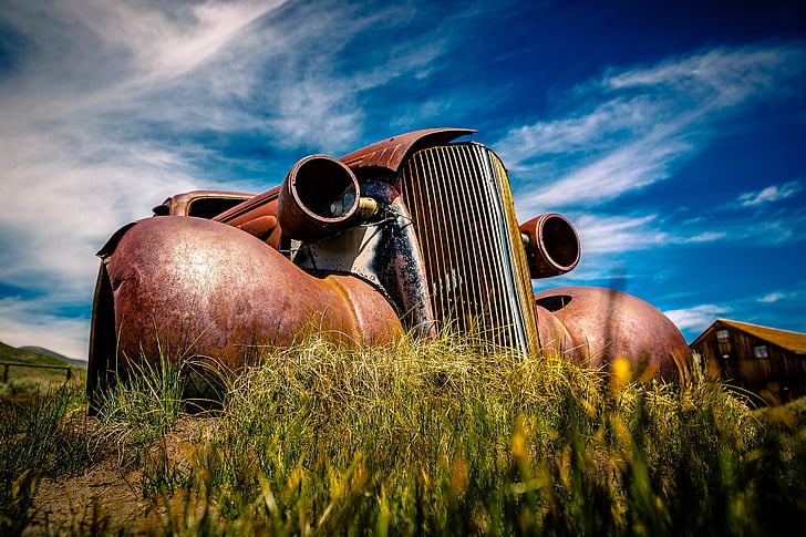 rusted vintage brown car under cloudy sky during daytime