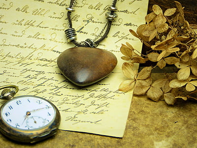 silver-colored pocket watch near brown heart pendant necklace on printer paper