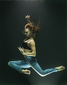 woman wearing black bra and blue denim pants dancing under water