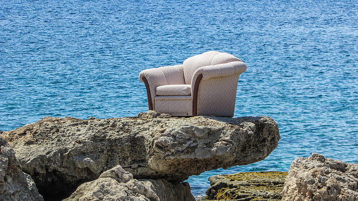 gray fabric sofa on top of brown rock near beach during daytime