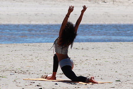 photo of woman wearing gray top kneeling on brown sand during daytime
