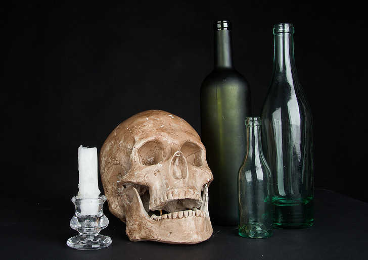 brown skull, white candle and three glass bottles