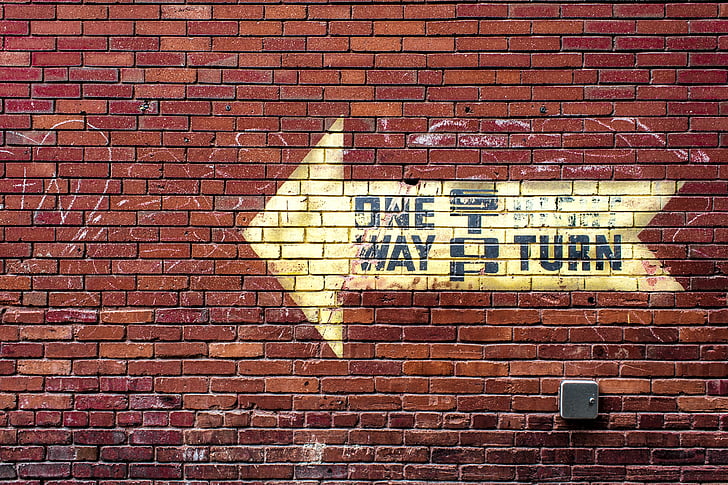 One Way signage on red brick wall