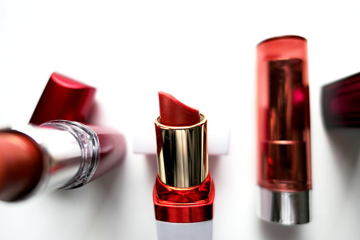 three red lipsticks on white surface close-up photography
