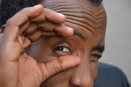 man touching his eye with two fingers