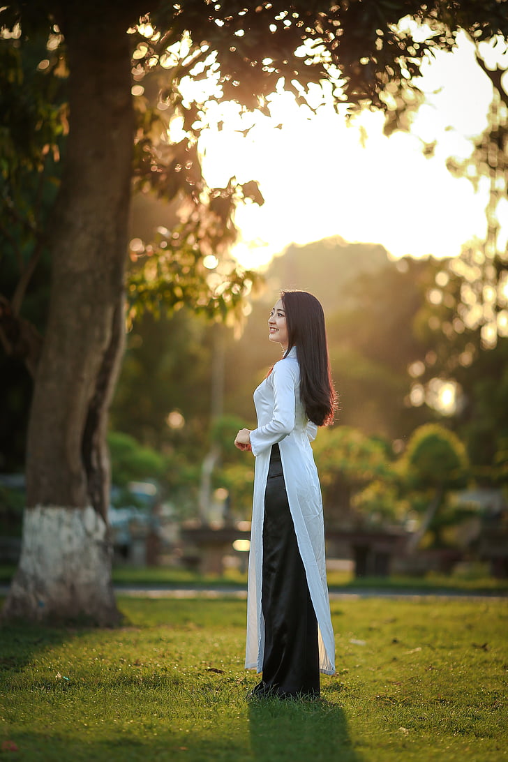woman in white dress standing near tree