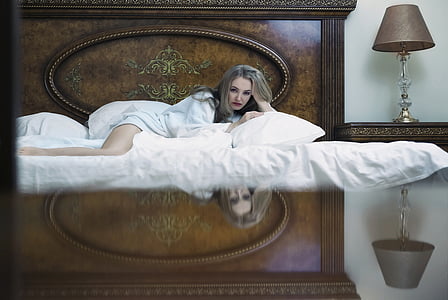 woman wearing white top laying on bed