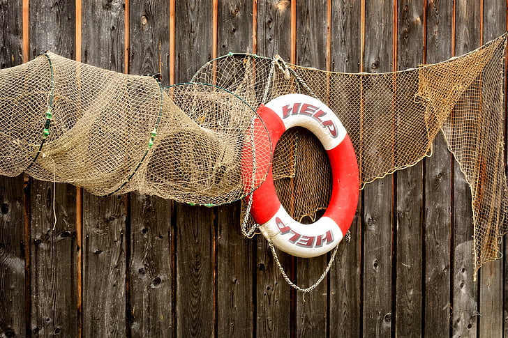 red and white lifebuoy hanged on wooden wall