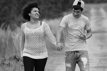 grayscale photography of man and woman holding hands while walking