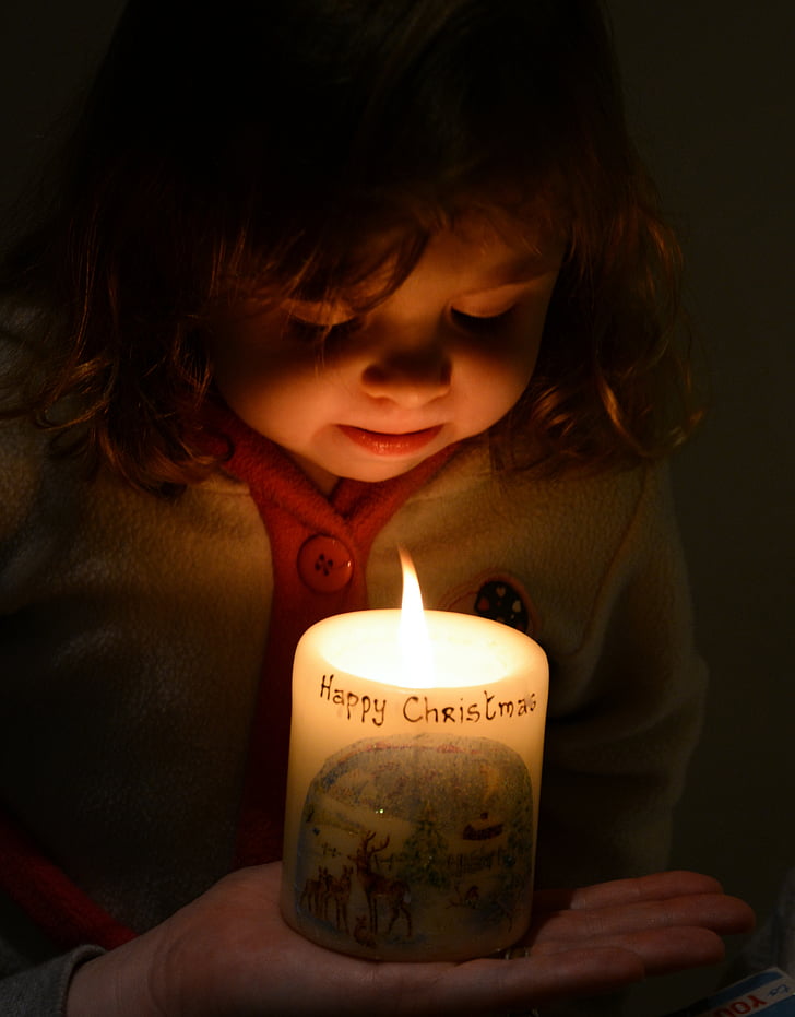 girl facing at lit pillar candle
