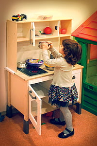 girl in gray and blue floral long-sleeved dress playing kitchen play set