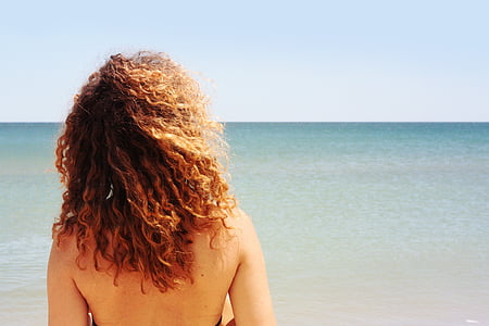 topless woman in front on sea at daytime