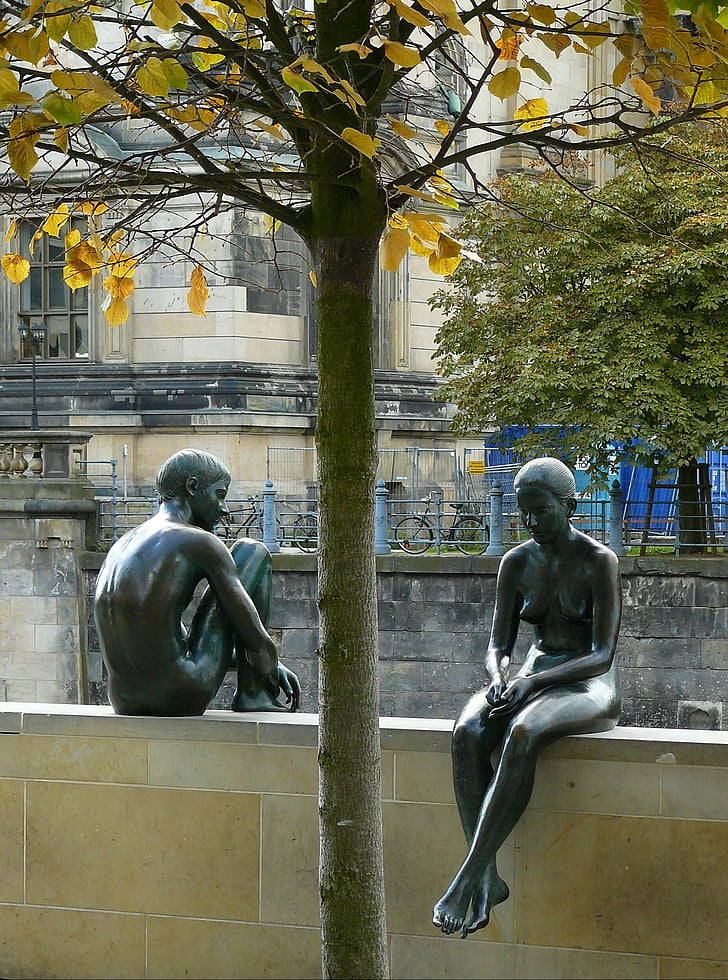 man and woman statue on beige concrete fence