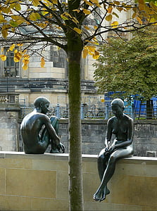 man and woman statue on beige concrete fence
