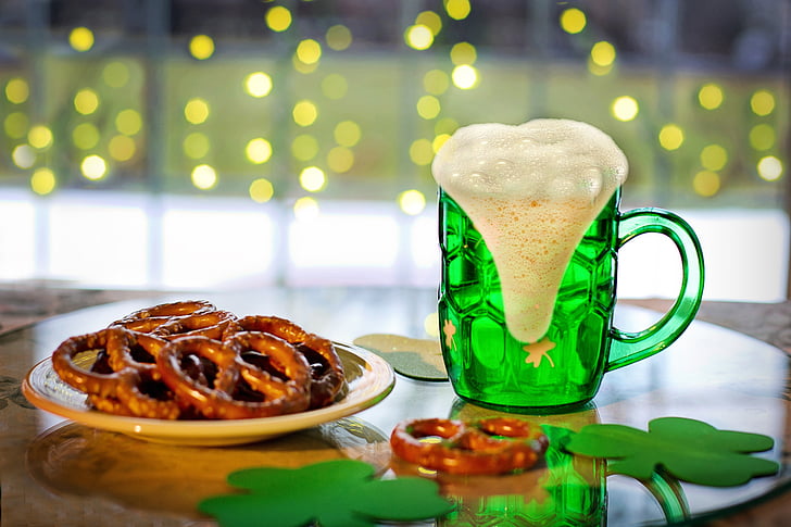 green glass beer stein and pretzel filled white plate