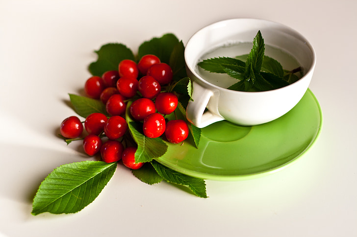 green hear near red fruit and white ceramic cup