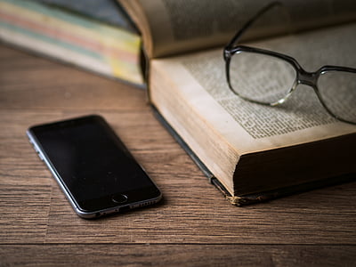 space gray iPhone 6 near eyeglasses and book
