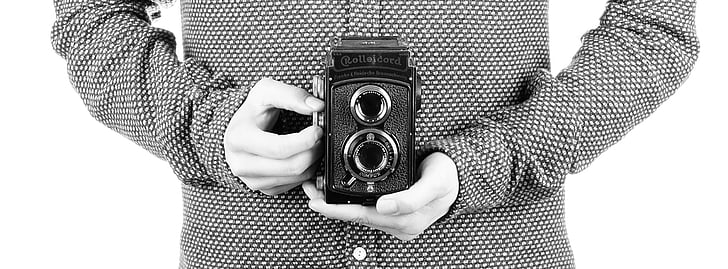 grayscale photography of person holding classic camera