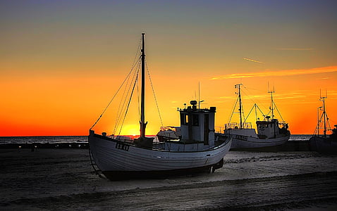white boat on shore during sunset
