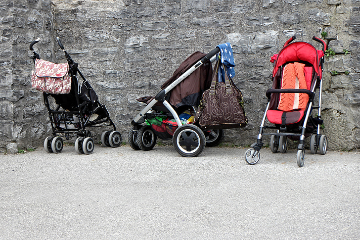three empty strollers beside wall