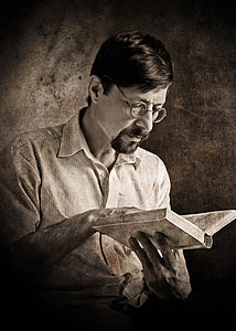 man wearing eyeglasses reading book