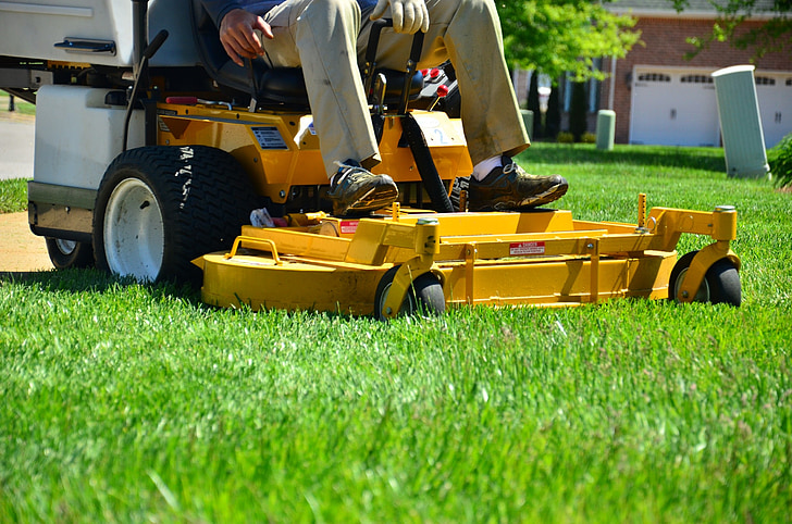 person sitting on yellow zero-turn lawn mower