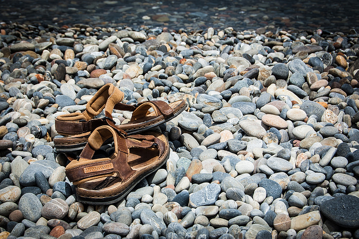 pair of brown sandals on gray stones