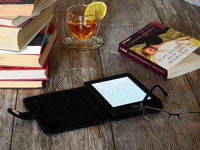 black e-book reader beside eyeglasses