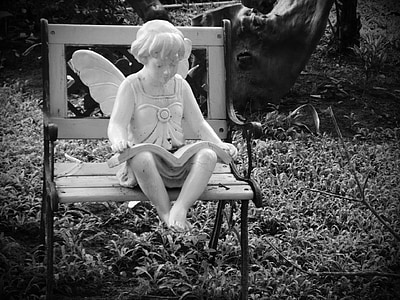 grayscale photography of fairy statue sitting on bench