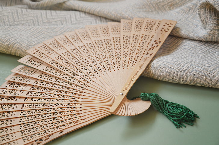 beige hand fan beside beige knitted textile