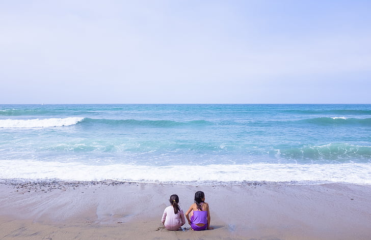 two girls sitting on seashore