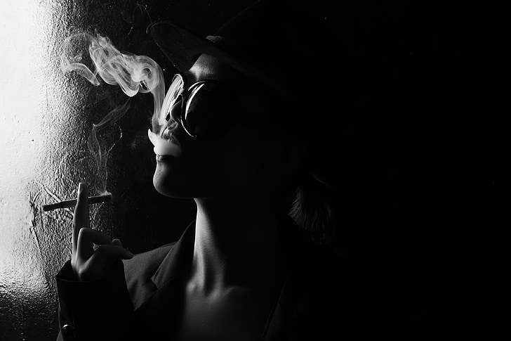 person smoking in grayscale photography